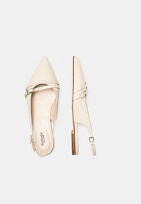 Scarpe slingback in pelle verniciata beige con punta affusolata, due cinturini incrociati e un tacco basso. Fibbia regolabile sul cinturino.