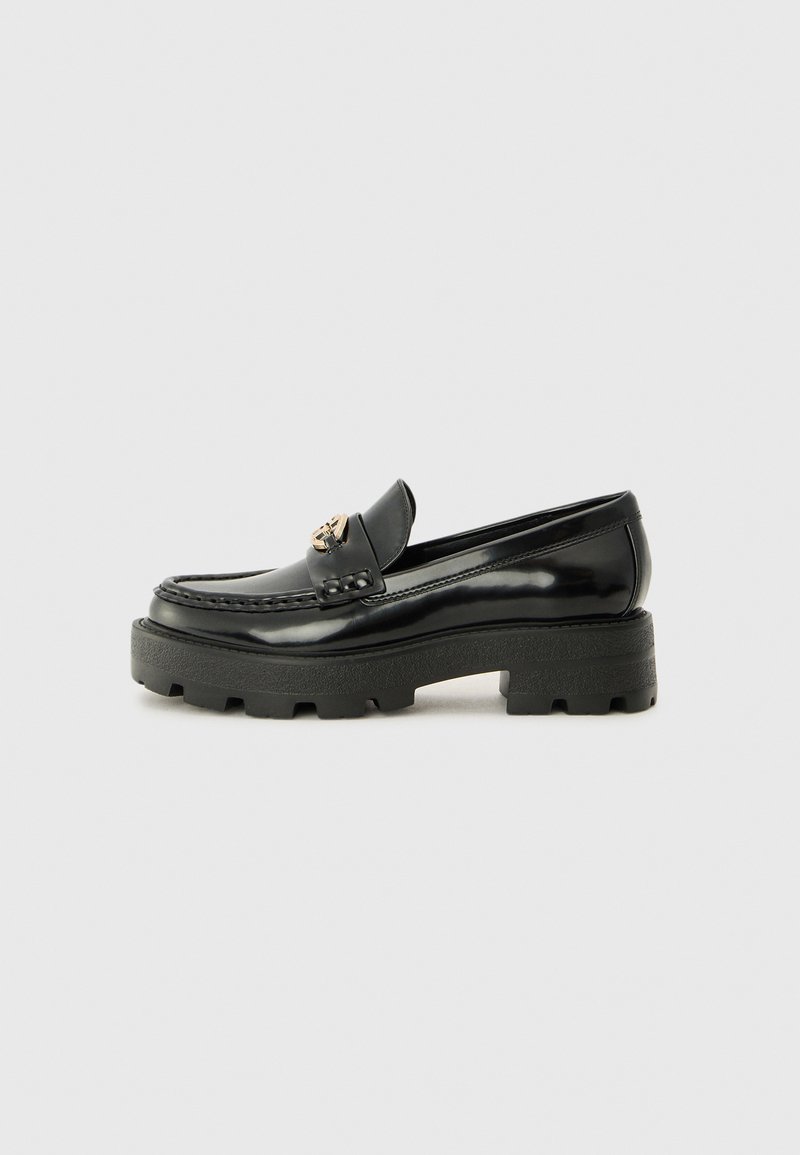Zwarte patenten leren loafers met een chunky zwart rubbersole, met een decoratieve hardware accent in goudkleur aan de voorkant.
