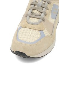 Beige tenniseket, millel on sametist ja võrgusilma ülemine osa, tugevdatud hallid aktsendid, ümar varvas ja tekstureeritud must kummist tald.