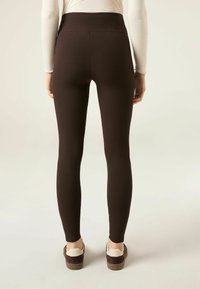 Bruine geribbelde leggings met een hoge tailleband, aangesloten design en vochtafvoerende stof. Gecombineerd met instap-sneakers.