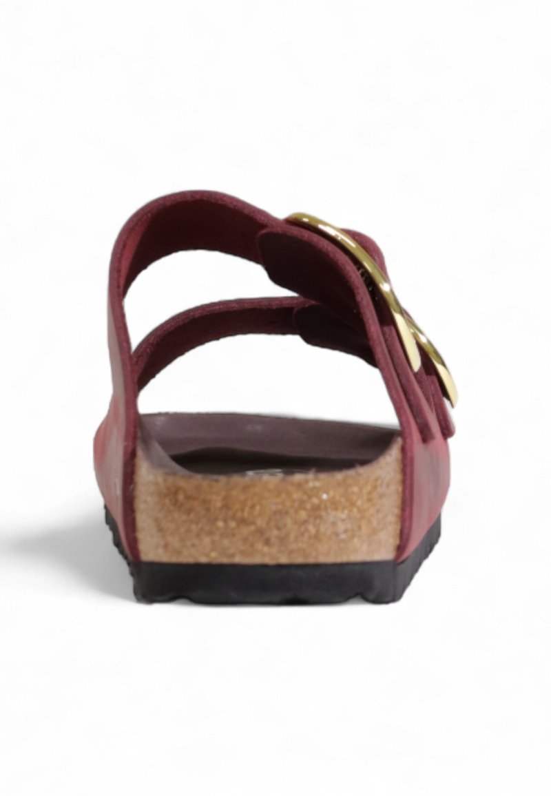 Sandale bordeaux avec deux brides et un détail de boucle dorée. Semelle en liège avec une semelle extérieure en caoutchouc noir texturé pour une meilleure adhérence.