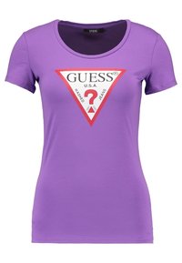 Paarse T-shirt met korte mouwen van katoen, met een rood en wit driehoekig logo en de tekst "GUESS U.S.A." in het midden. Fijne textuur.