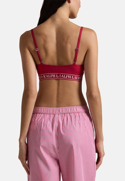 Röd bralette med logoband, justerbara axelband och en slät yta. Kombinerad med rosa och vita randiga pyjamasbyxor med resår i midjan.