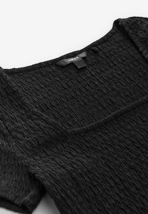 Haut noir texturé avec un décolleté carré, des manches courtes et un subtil détail de tissu froissé. Comprend une étiquette dans la zone intérieure du cou.