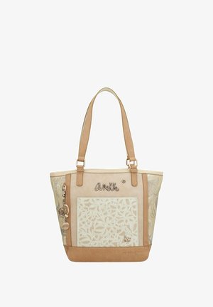 Sac fourre-tout beige avec motif floral brodé, accents en cuir, doubles poignées et charms décoratifs. Texture lisse avec une forme structurée.