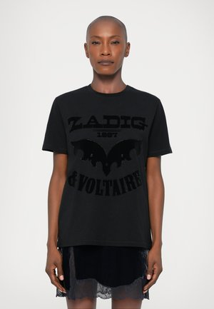 Camiseta de algodão preta com um design de morcego e o texto "ZADIG 1987 & VOLTAIRE" em tecido preto em relevo. Manga curta e decote redondo.