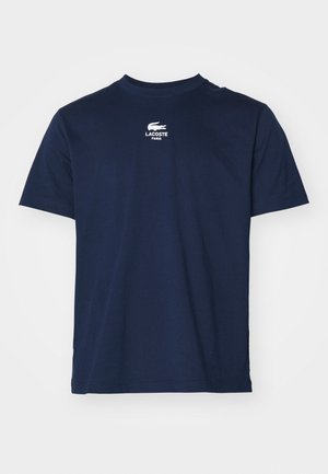 T-shirt bleu marine à manches courtes avec col rond et logo Lacoste Paris blanc avec emblème de crocodile centré sur la poitrine.