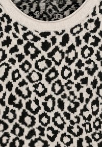 Schwarz- und cremefarbenes Strickgewebe mit einem Leopardenmuster, das sich durch unterschiedliche Flecken Größen und Texturen auszeichnet. Rundhalsausschnitt mit geripptem Saum.