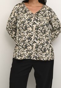 Blomstret v-neck bluse med et cremet og mørkt design med grønne accenter, lavet af letvægtsstof og lange ærmer. Sammen med mørke bukser.