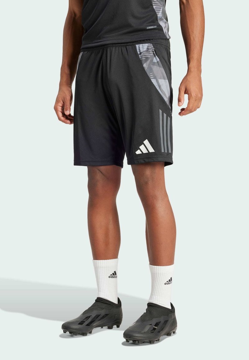 Schwarze Sportshorts mit einem grauen gemusterten Seitenpanel, ausgestattet mit drei weißen Streifen und einem elastischen Bund, kombiniert mit schwarzen Fußballschuhen und weißen Socken.