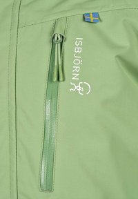 Ljusgrön jacka med dubbla dragkedjor på fickan, vit ISBJÖRN-logotyp och en liten svensk flagga ovanför logotypen.