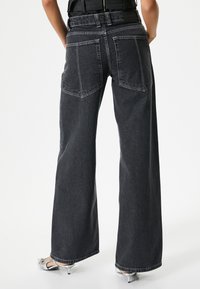 Jeans de tiro alto y pernera ancha en denim gris oscuro con costuras en contraste y dos bolsillos traseros. Adecuados para un uso casual.