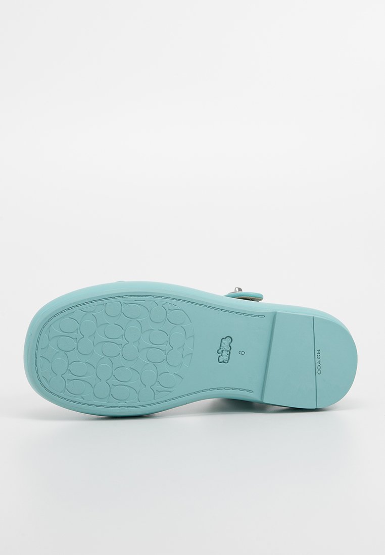 Turkusowa gumowa podeszwa sandałów z teksturowanym, wzorzystym chwytem i logo marki. Płaski design, gładka powierzchnia i zaokrąglone krawędzie.