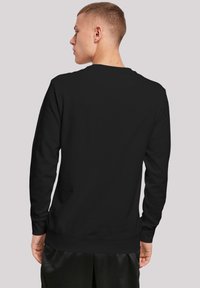 Sudadera de cuello redondo negra hecha de una mezcla de algodón, presenta mangas largas y un dobladillo acanalado. La vista trasera muestra un diseño suave y minimalista.