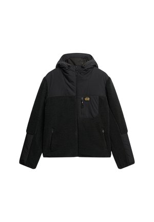 Chaqueta negra con capucha que combina forro polar y tejido suave, con bolsillos con cremallera y un parche con el logo en el pecho.