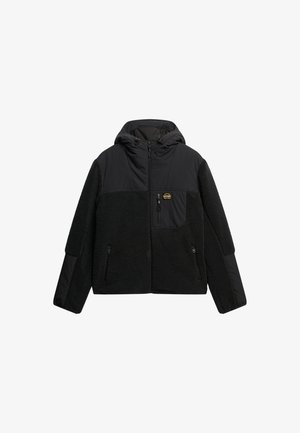 Zwarte gebonden jas met een mix van fleece en gladde stof, voorzien van ritssluiting zakken en een logo patch op de borst.