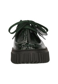 Zapato de charol verde con puntera redondeada, suela negra gruesa y cordones verdes. Presenta una textura suave y un acabado brillante.