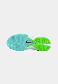Sål af hvid Nike sportsko med tekstureret blå forkant, grøn hæl og sort swoosh-logo i midten.
