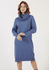 Robe tricotée bleue avec un col cheminée, des manches longues et des accents de boutons sur les côtés. Texture lisse et coupe à mi-cuisse.