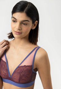 Lila Spitzen-Bralette mit tiefem V-Ausschnitt, transparenten Netzpaneelen und verstellbaren Trägern. Das Design vereint Weichheit und filigrane Details.