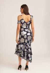 Navy blue dress with silver floral embroidery, off-shoulder design, ruffled hem, and a fitted silhouette, paired with black heels.