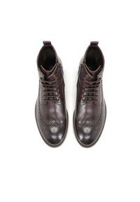 Botas de cuero burdeos hasta el tobillo con detalles de brogue, puntera redonda, diseño clásico de cordones y suela de goma blanca contrastante.