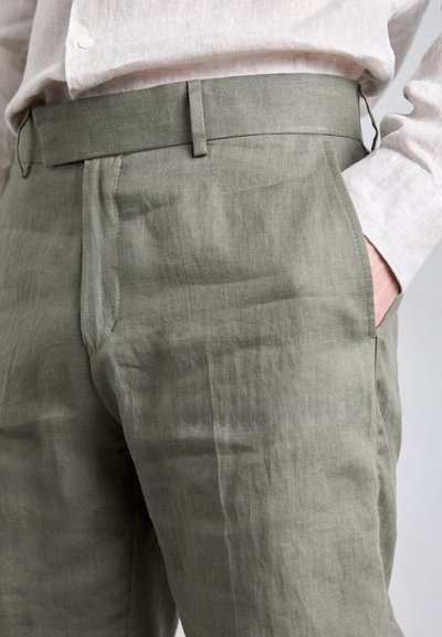 Pantaloni din in verde deschis, cu o croială relaxată, prezentând un front plat, buzunare laterale și o talie. Textură fină și minimă împăturire.