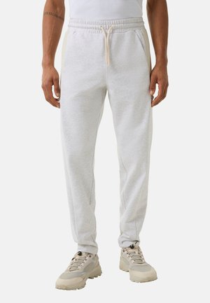 Lysegrå bomuldsjoggers med elastisk talje, snørre og sidelommer, parret med lyse atletiske sko.
