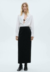 White button-up shirt with an open collar, paired with a long black fitted skirt and ankle boots. Smooth fabric with minimal design details.