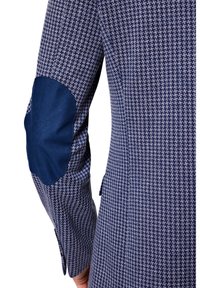 Rękaw marynarki w granatowym i jasnoniebieskim wzorze houndstooth, z gładką granatową łatą na łokciu, dopasowany krój i detal w postaci bocznej kieszeni.