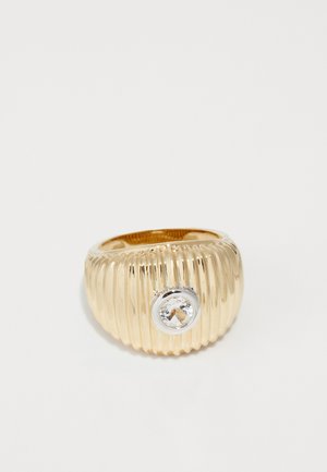Gold ribbed ring with a round, clear gemstone set in a silver bezel. Smooth, shiny surface with a textured design.