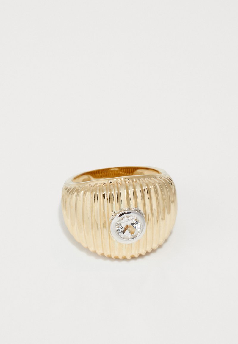 Arany bordázott gyűrű kerek, tiszta drágakővel, amely ezüst keretben van foglalva. Simogató, fényes felület, textúrált mintázattal.