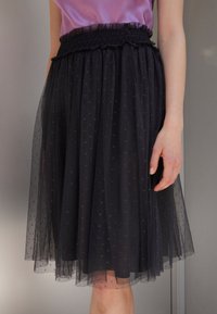 Gonna in tulle nero con vita arricciata, caratterizzata da piccoli motivi a forma di stella, lunghezza al ginocchio e trama trasparente a strati.