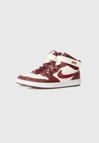 Baskets montantes Nike en cuir bordeaux et crème. Présentent une cheville rembourrée, une semelle blanche et une sangle Velcro. Logo affiché sur le côté.