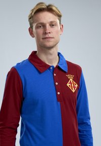 Langmouw rugbyshirt met een blauw en kastanjebruin gesplitst ontwerp, met een kraag, knopen en een geborduurd logo in goud.