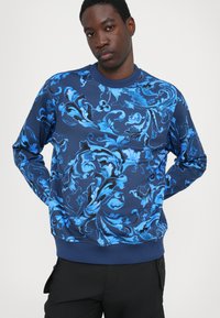 Navy sweatshirt med et blått blomsterdesign, rund halslinning, ribbede mansjetter og nederkant, laget av myk, teksturert stoff.