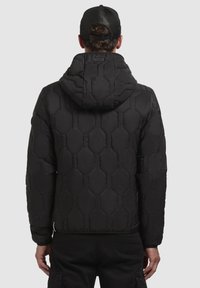 Schwarze Pufferjacke mit hexagonalem Steppmuster, Kapuze und elastischen Bündchen, die eine glatte, glänzende Textur aufweist.