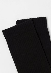 Calze nere a coste con una texture morbida, caratterizzate da un colore uniforme e un bordo ripiegato nella parte superiore. Adatte per l'uso quotidiano.