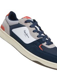 Navy and grey sneaker with suede and mesh materials, white accent panel, orange heel tab, and navy laces. Features branded logo on side.