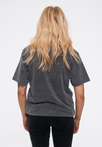 Gray oversized t-shirt with short sleeves, soft texture, relaxed fit, and a rounded hem, worn with black fitted pants.