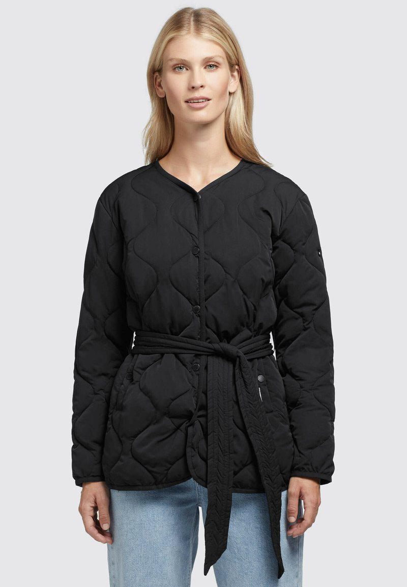 Zwarte gewatteerde jas met een V-hals, knoopsluiting en een strikceintuur. Beschikt over een gestructureerd oppervlak en lange mouwen, gestyled met rechte blauwe jeans.