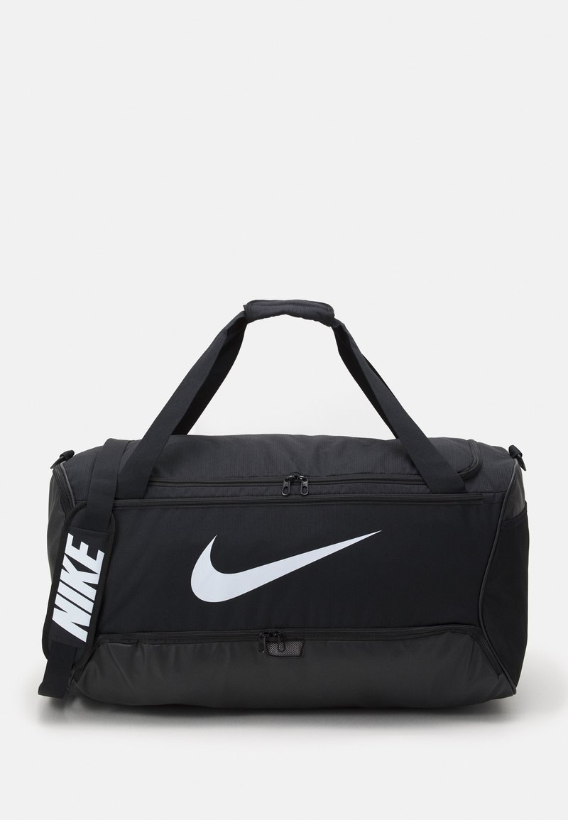 Borsa da palestra nera con un grande logo Nike bianco a forma di baffo, doppi manici per il trasporto, tracolla regolabile e scomparti con zip.