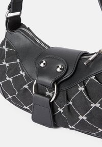 Čierna ramenná taška s prešívaným vzorom, strieborným prešívaním, zipsom a čiernymi koženými detailmi s kovovými príchuťami.
