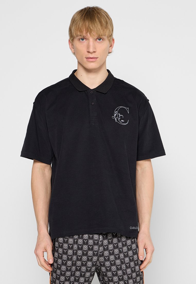 Zwarte polo in een katoenmix, met een gestructureerde kraag, een drieknoopsluiting en een geborduurd "C" op de borst.