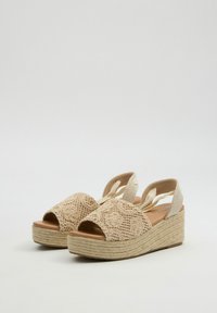 Sandalias de cuña en beige con diseño bordado en la parte superior, punta abierta y correas ajustables. La entresuela envuelta en yute añade textura.