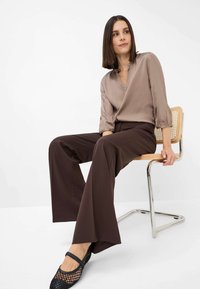 Satin beige wrap blouse with three-quarter sleeves, paired with wide-leg brown trousers. Black mesh ballet flats complete the outfit.