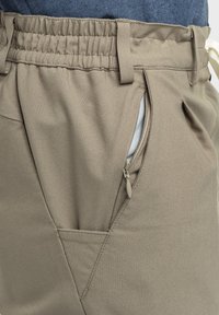 Khakihosen mit elastischem Bund, schrägem Seitentasche mit Reißverschluss und genähten Details für ein strukturiertes Erscheinungsbild.