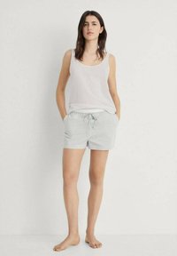 Witte mouwloze top gecombineerd met lichtgrijze gestreepte shorts met een trekkoord in de taille en twee zijzakken. Soepele textuur, casual pasvorm.