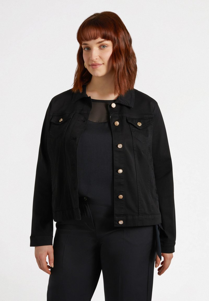 Veste en denim noire avec des fermetures à bouton et deux poches avant ; présente un col classique et une coupe légèrement courte. Texture uniforme sur l'ensemble.