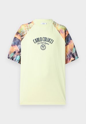 Hele kollase värvusega lühikeste varrukatega särk, millel on värviliste abstraktsete mustritega raglaanvarrukad ja ees tekst "Carlo Colucci The Knit Legend" koos logoga.